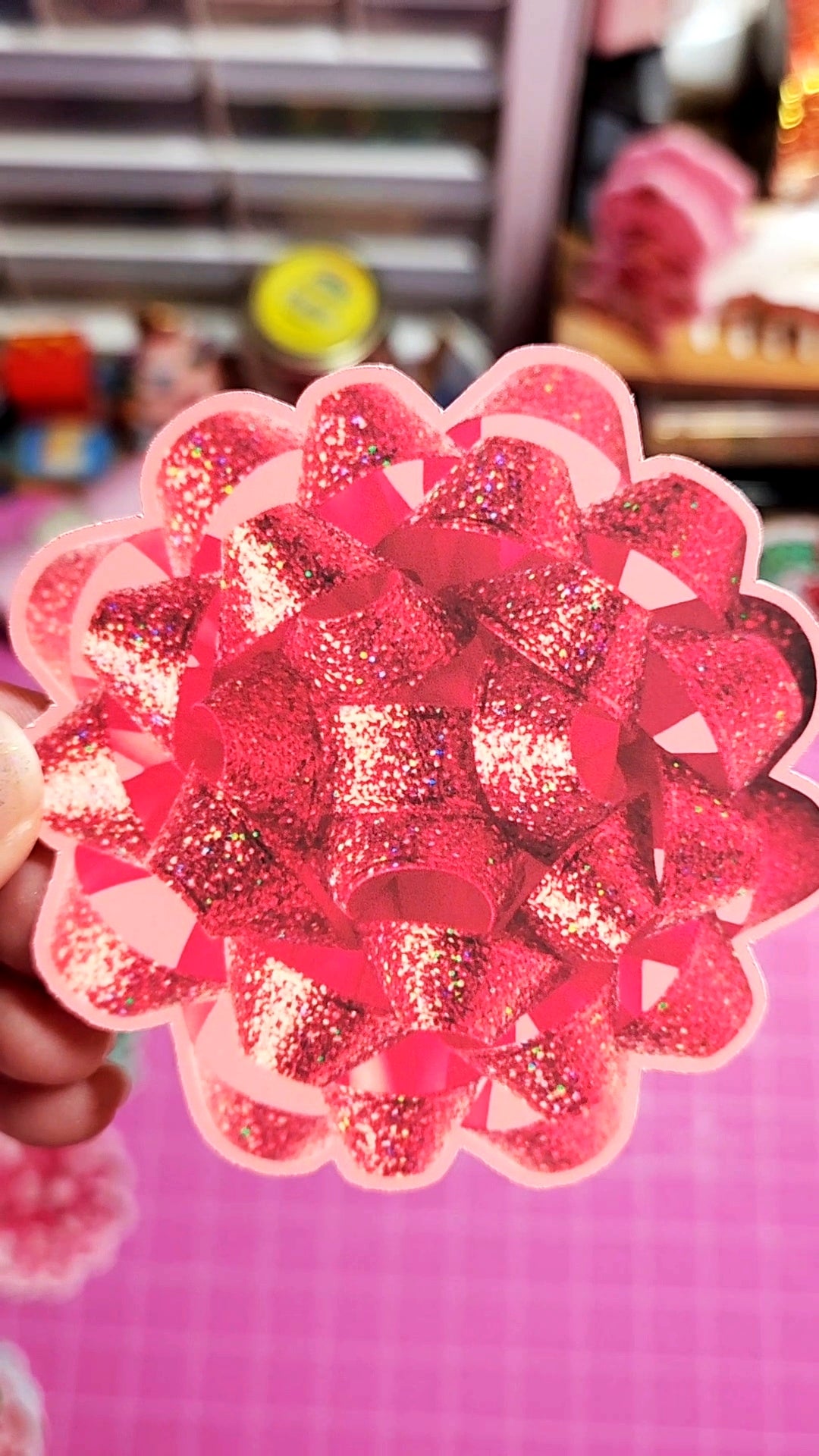 Decorative pink flower with glittery texture held against a blurred indoor background