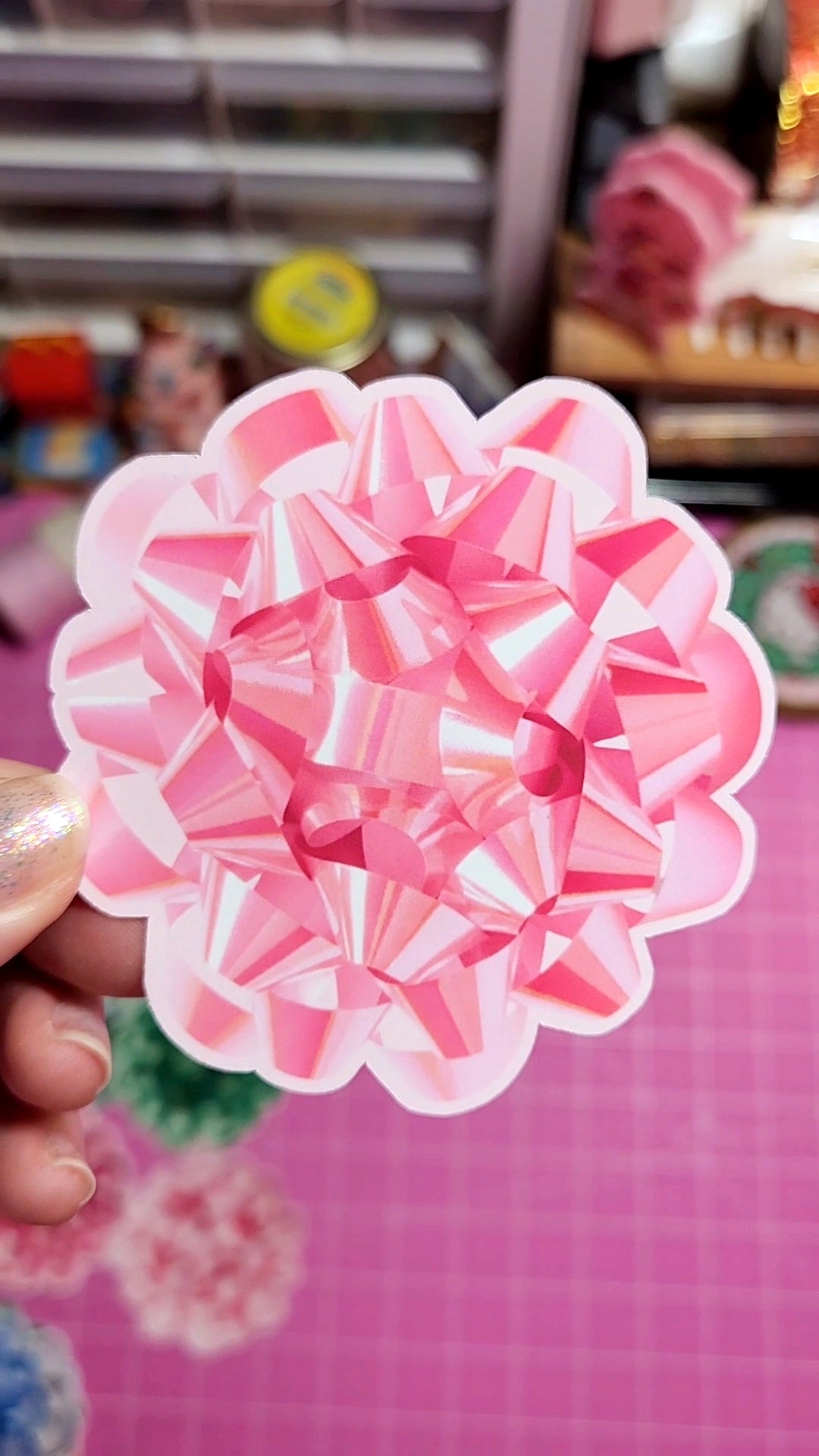 Pink and white geometric flower-shaped object held by a hand with a blurred background