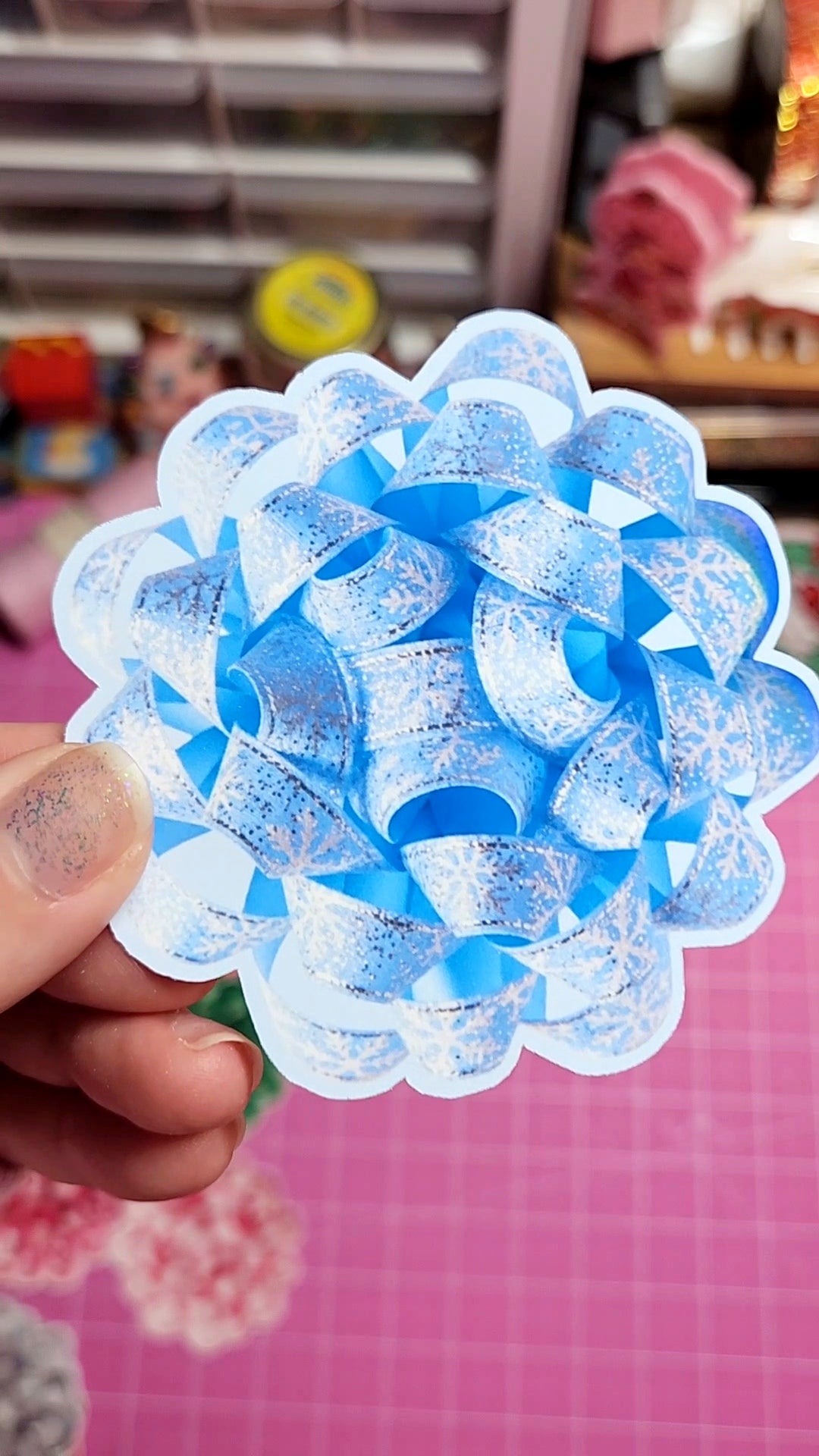 Blue decorative item held by a hand with a blurred background