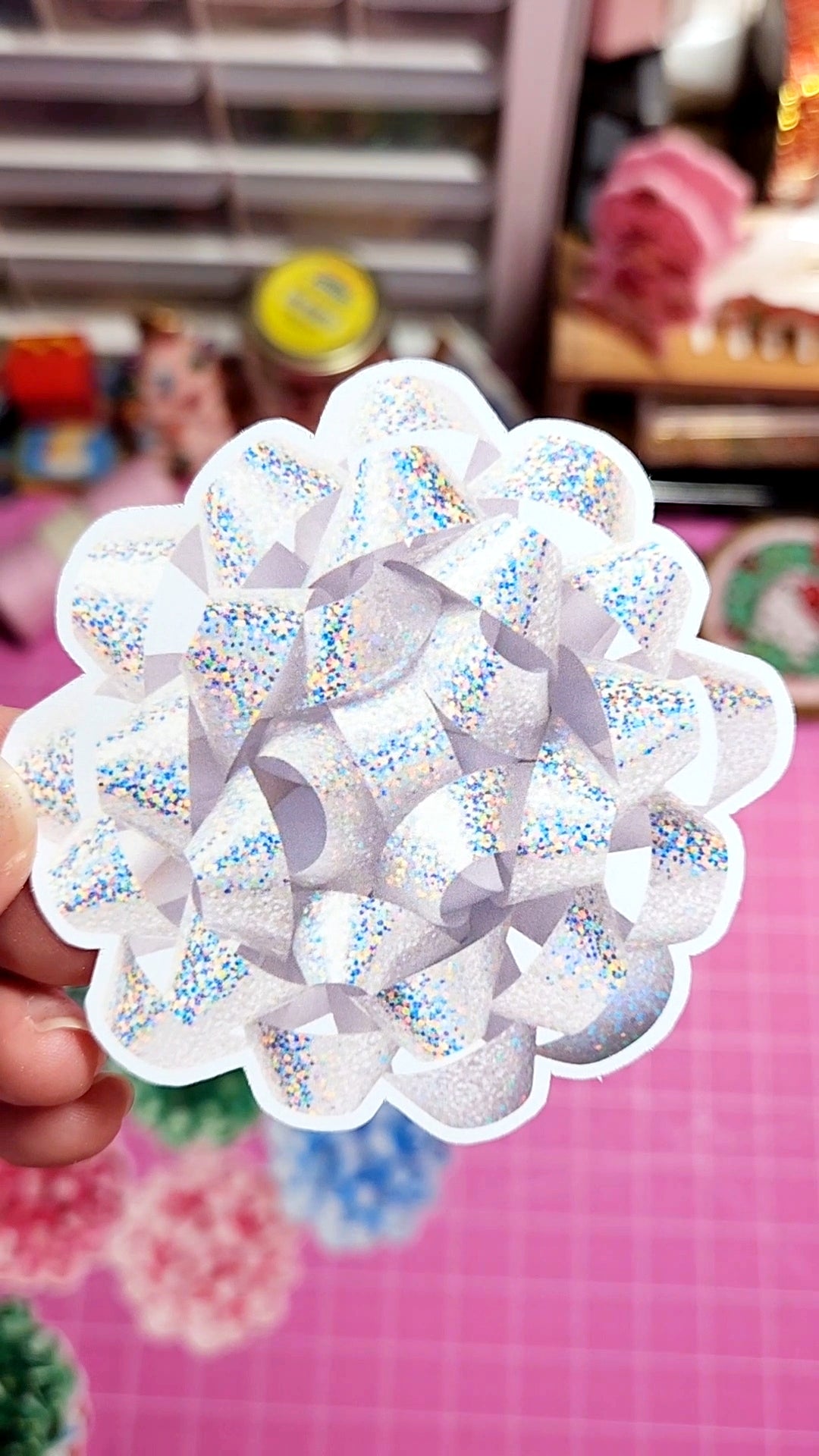 Decorative white object with colorful sprinkles held by a hand against a blurred indoor background