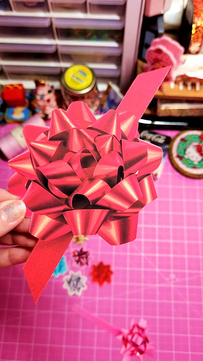 Red bow held in front of a colorful background with various objects.