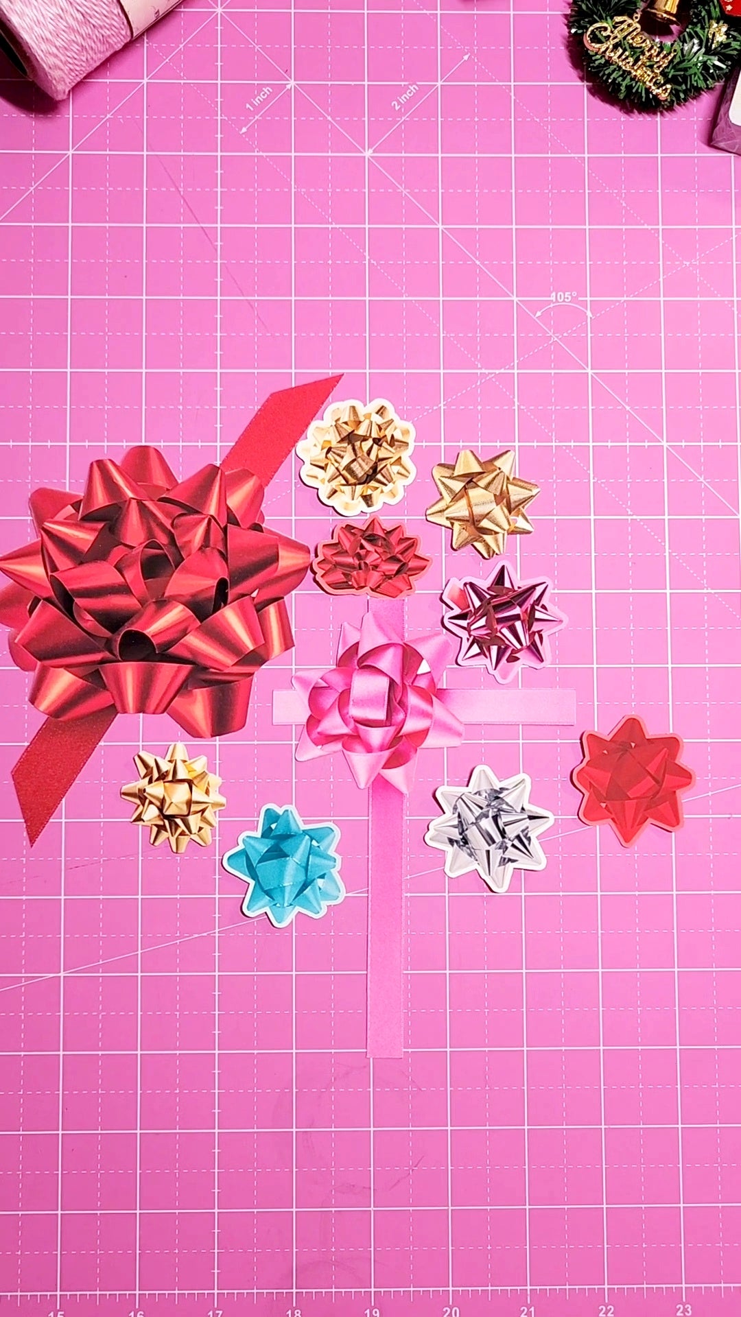 Colorful paper bows on a pink cutting mat with grid lines