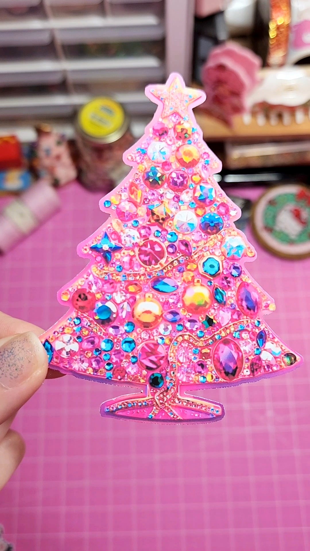 Colorful Christmas tree ornament with rhinestones on a pink background