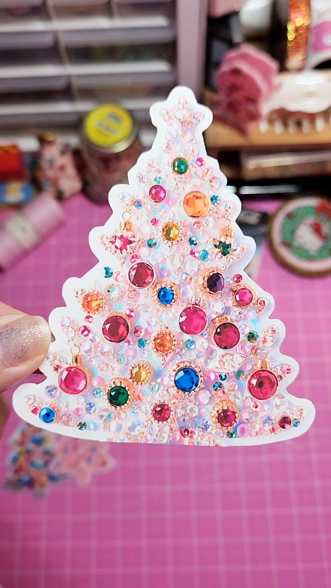 Decorative Christmas tree sticker with colorful gems on a pink background