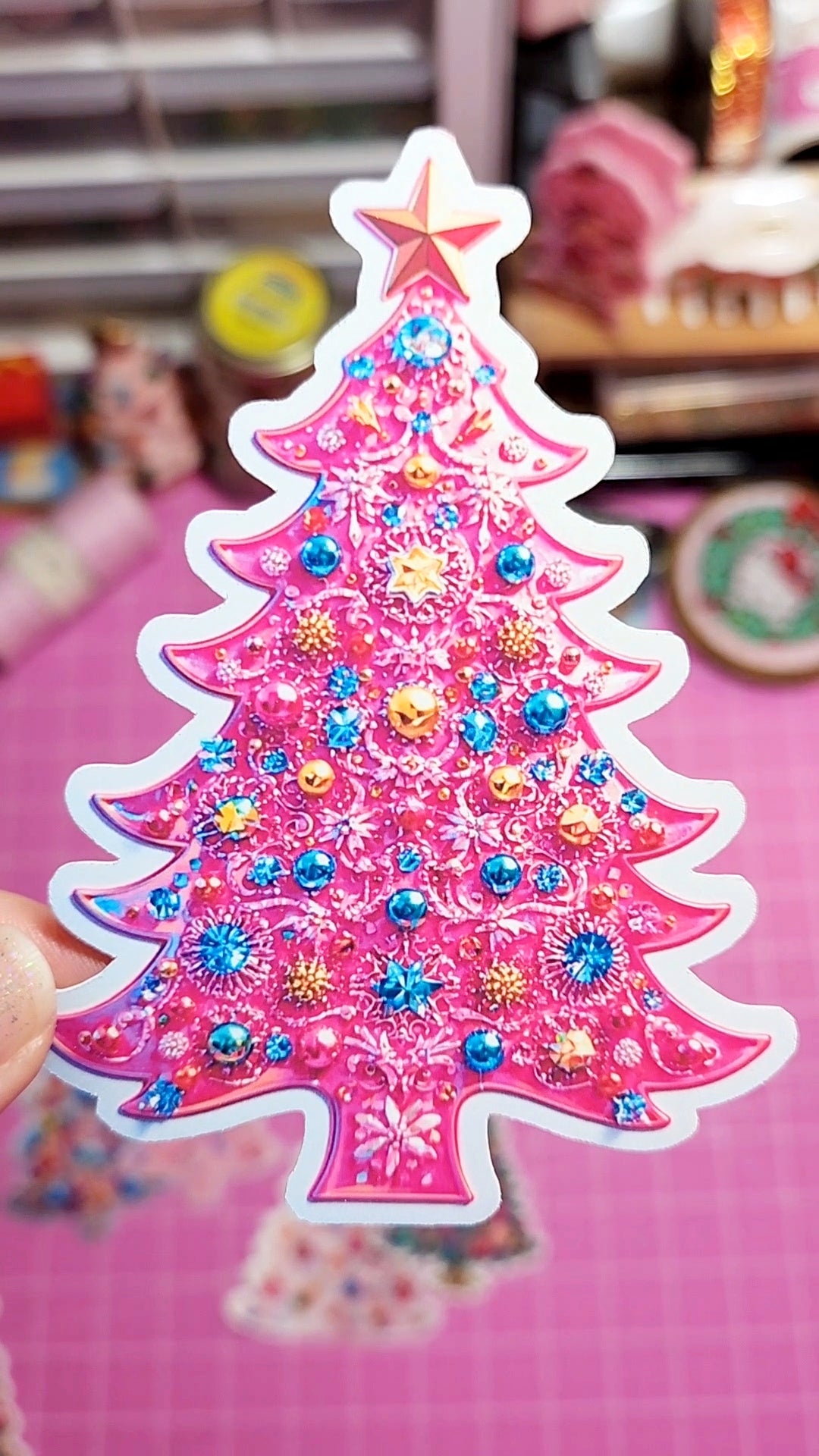 Decorative Christmas tree sticker with colorful embellishments on a pink background