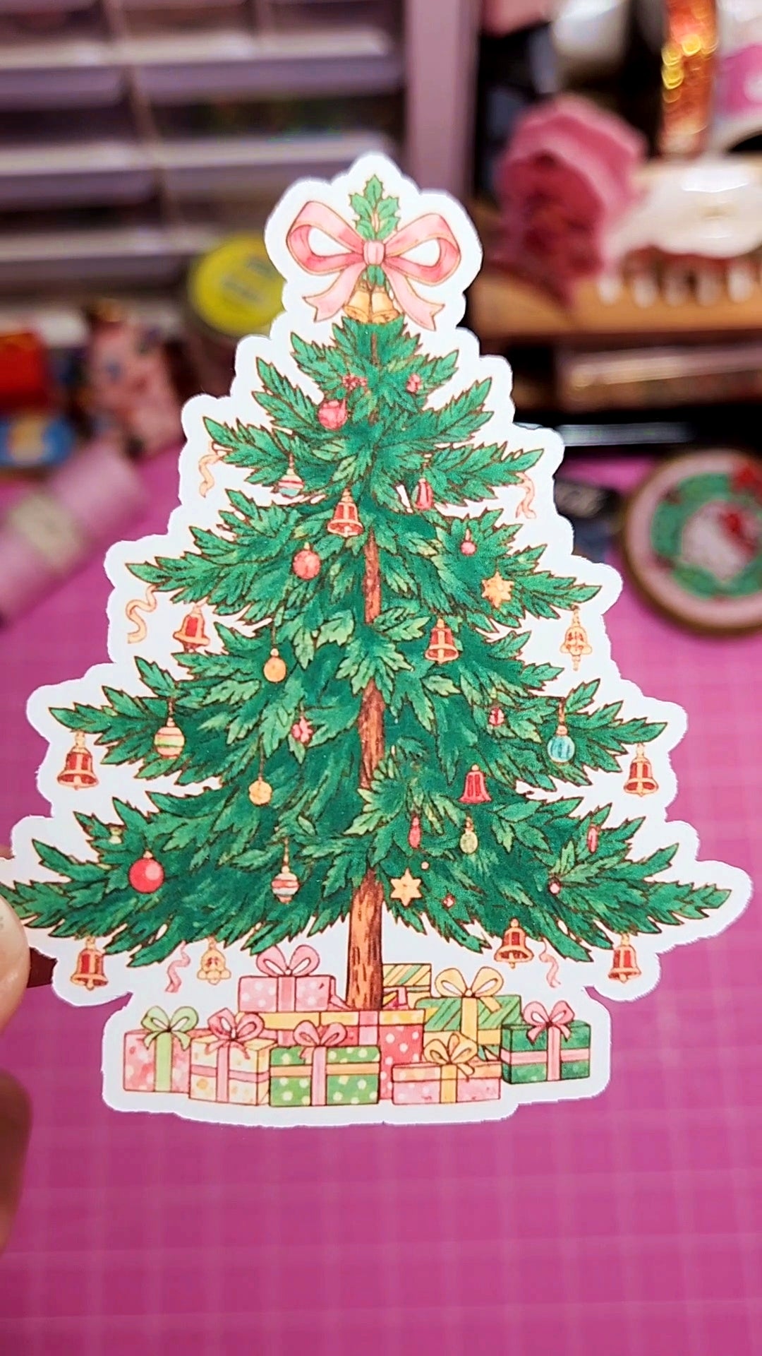 Sticker of a decorated Christmas tree with presents on a pink background