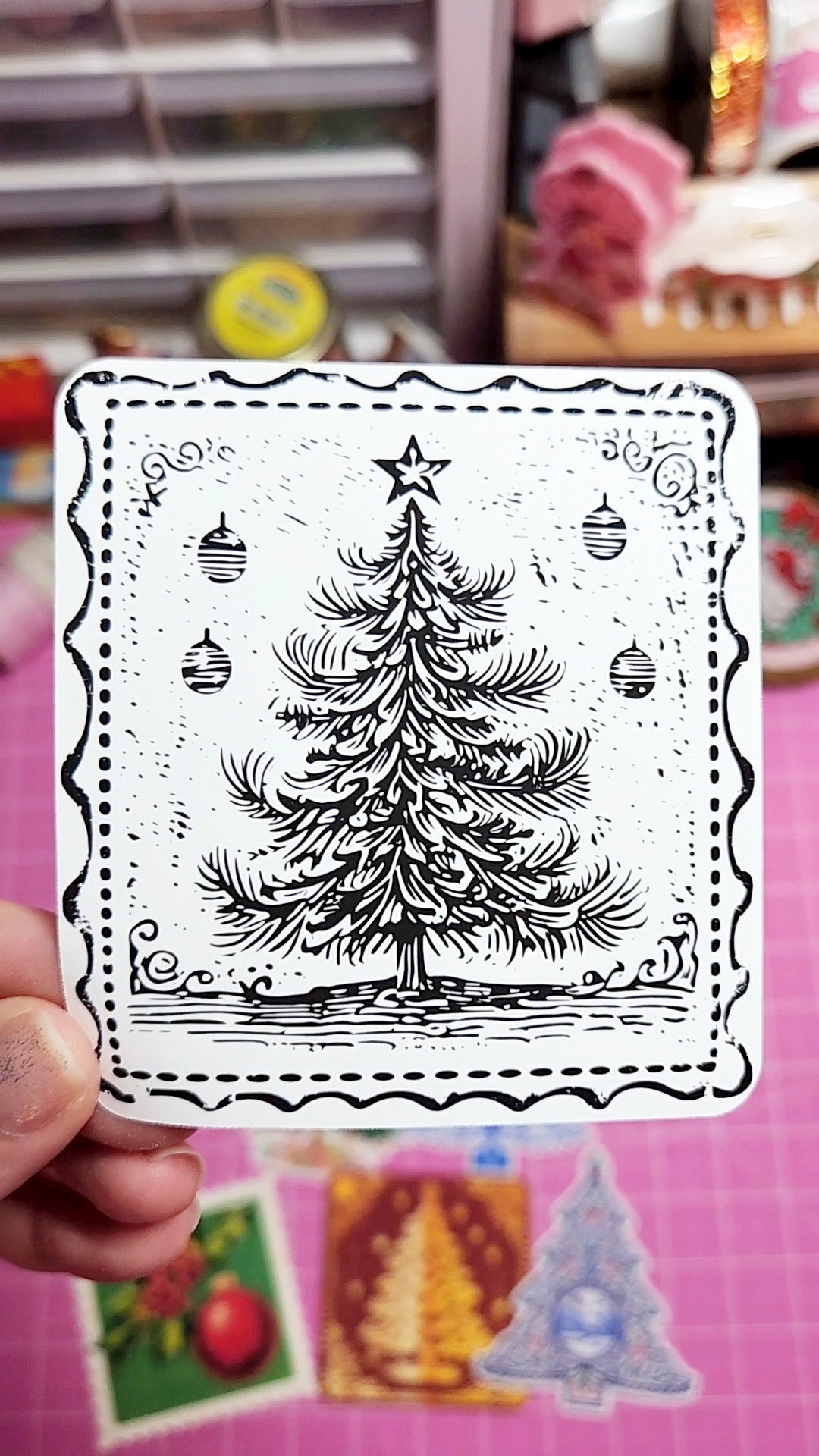 Black and white Christmas tree stamp held by a hand with a colorful background