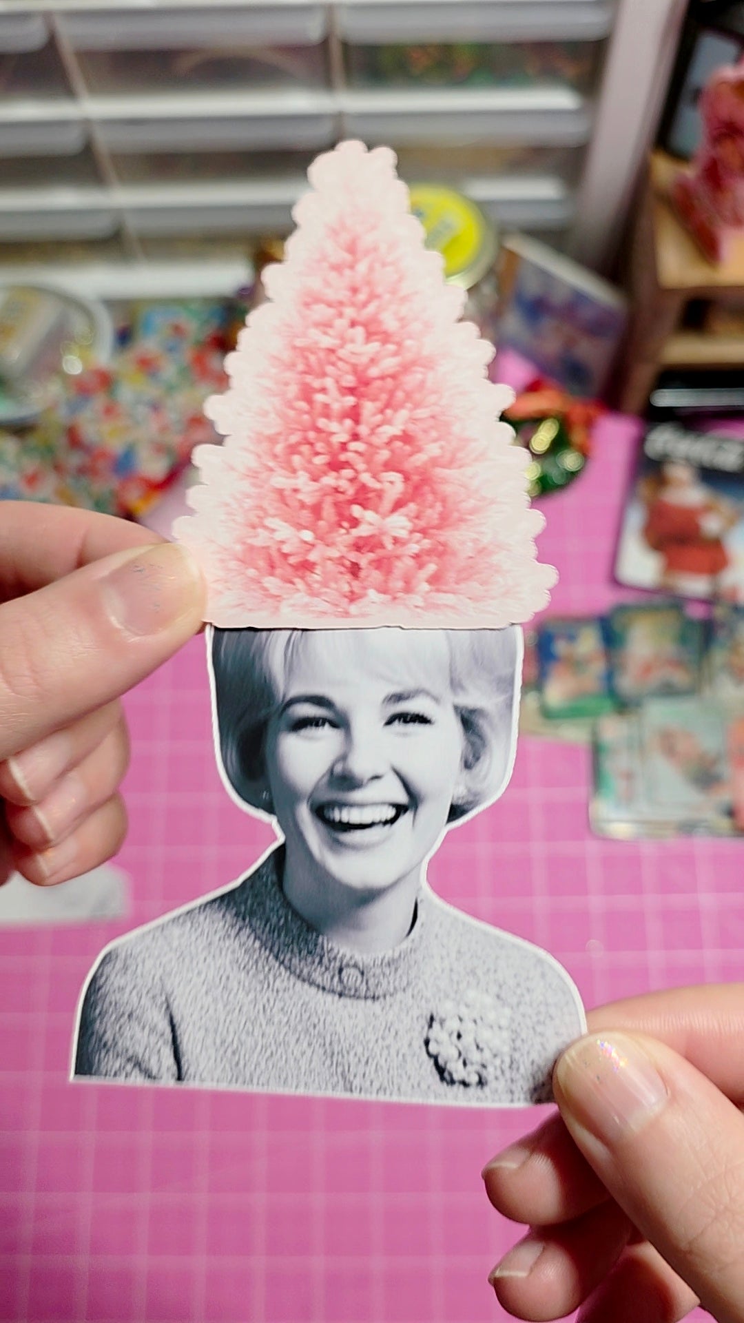 Person holding a cutout of a smiling woman with a pink and white cone-shaped object on top.
