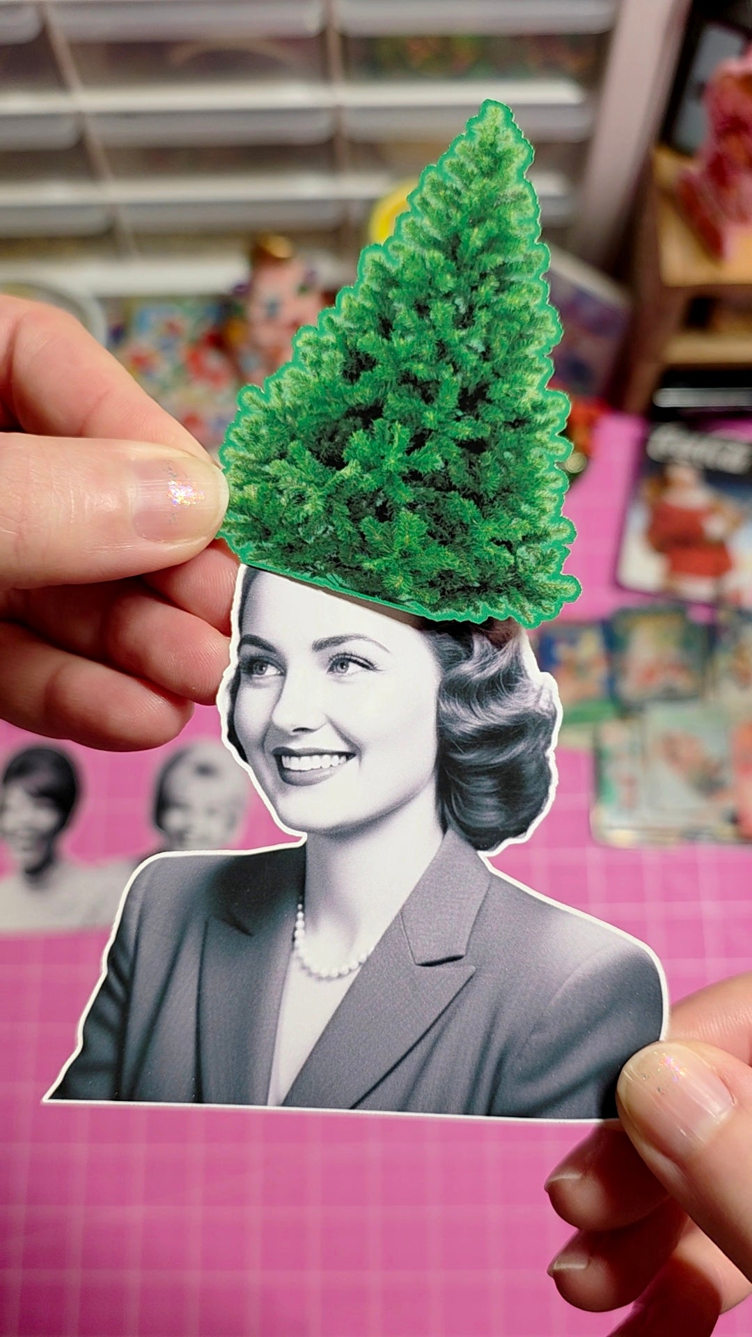 Person holding a cutout of a woman with a green tree on her head against a pink background with vintage photos.