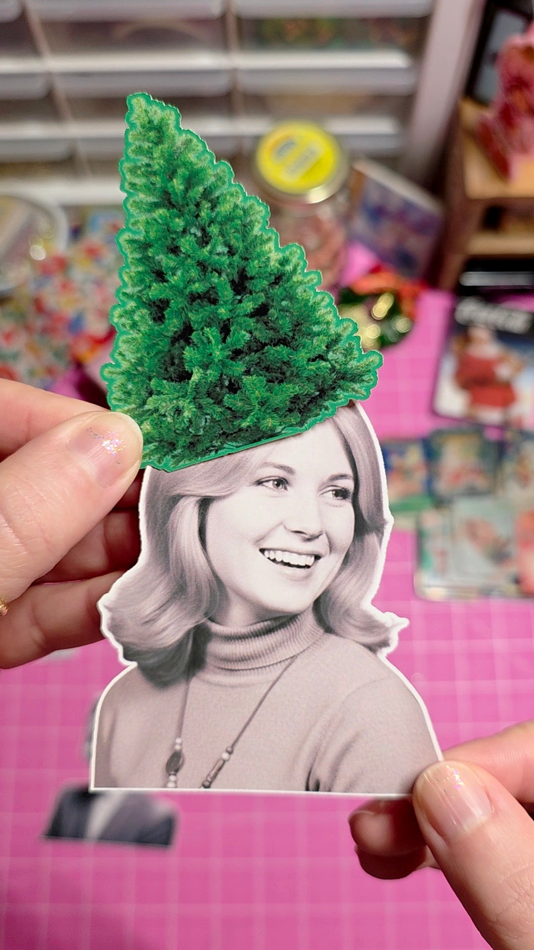 Person holding a photo of a woman with a green tree on their head against a colorful background.