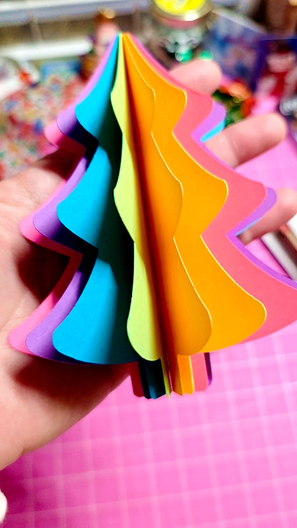 Colorful paper cutouts shaped like triangles held by a hand on a pink surface.