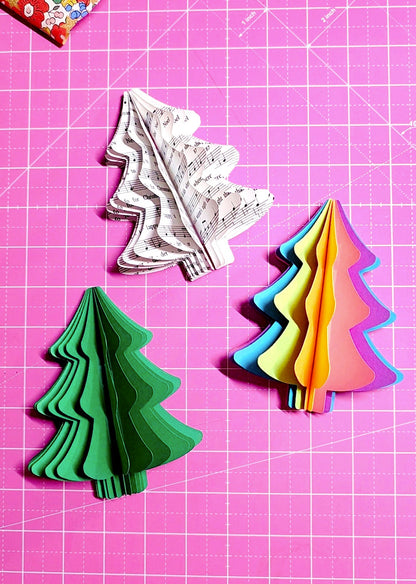 Colorful paper Christmas trees on a pink grid background