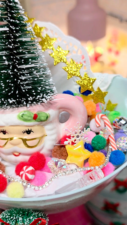 Decorative Christmas scene with a Santa Claus mug, candy, and tree.