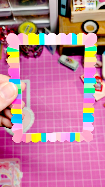 Colorful photo frame made of small colorful plastic pieces held over a pink grid background.