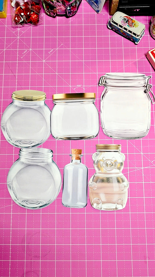 Set of glass jars with various shapes and sizes on a pink grid background