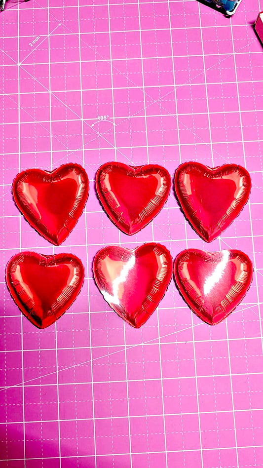 Six red heart-shaped objects on a pink grid background