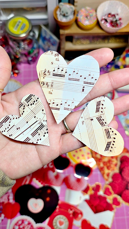 Heart-shaped stickers with musical notes held between fingers against a colorful background