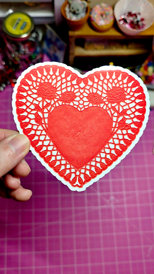 Red heart-shaped cutout with intricate patterns on a pink grid background