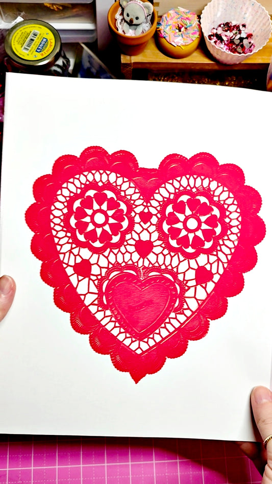 Heart-shaped paper cutout with intricate designs on a white background