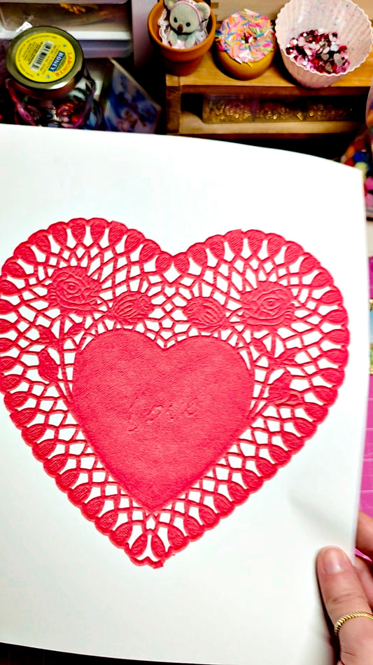 Red heart-shaped card with lace design on a white surface