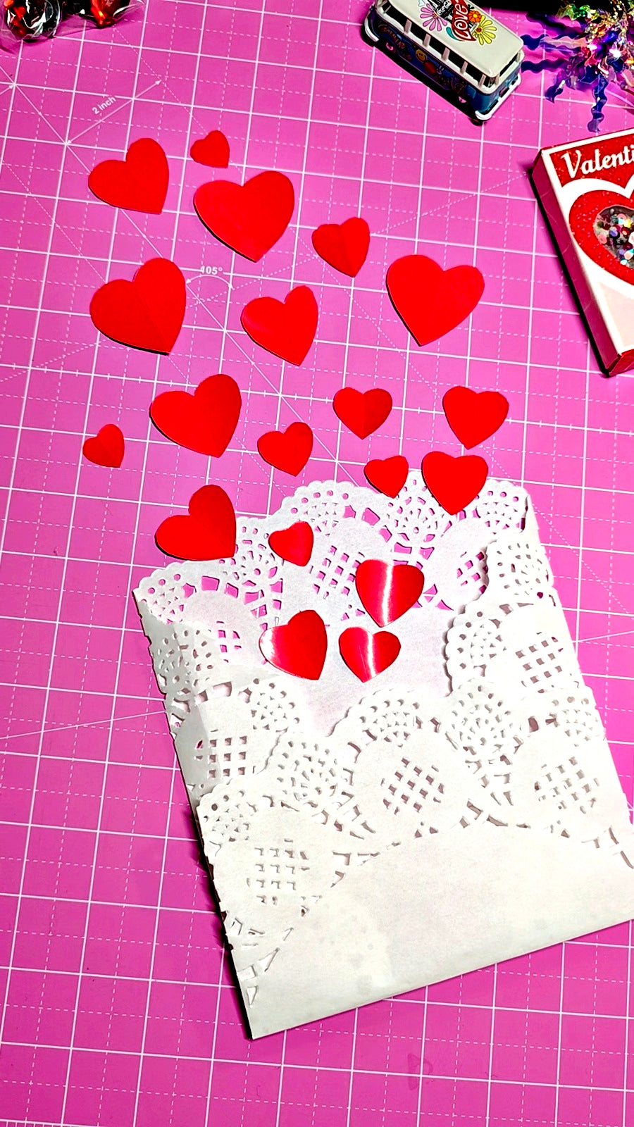 Red heart-shaped stickers on a white doily with a pink grid background
