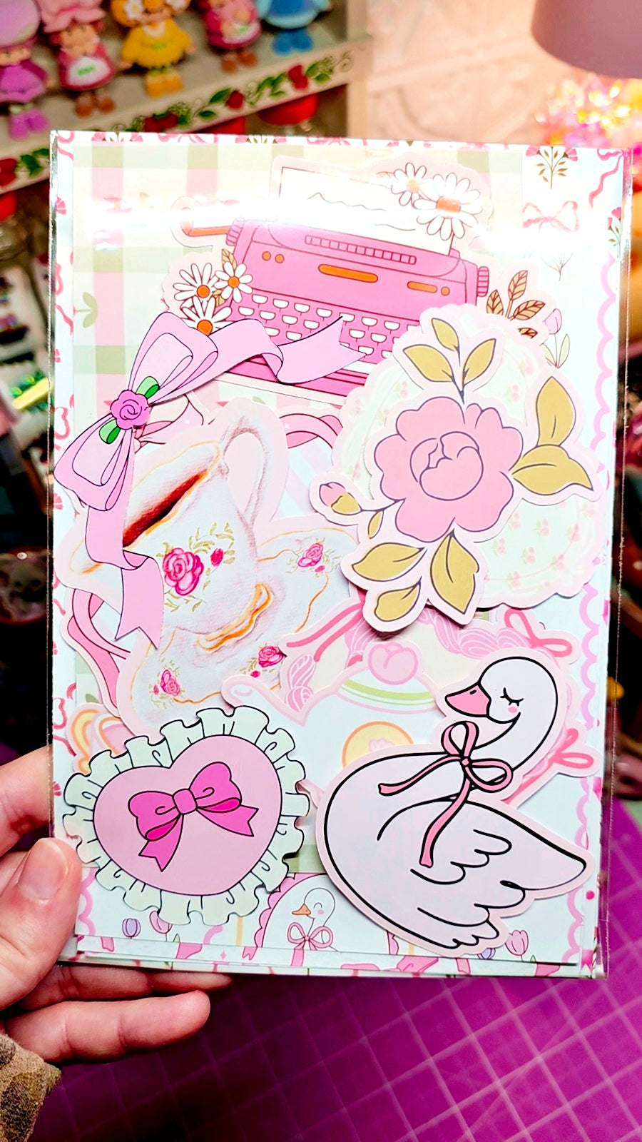 Decorative notebook with floral and bow designs held by a person.