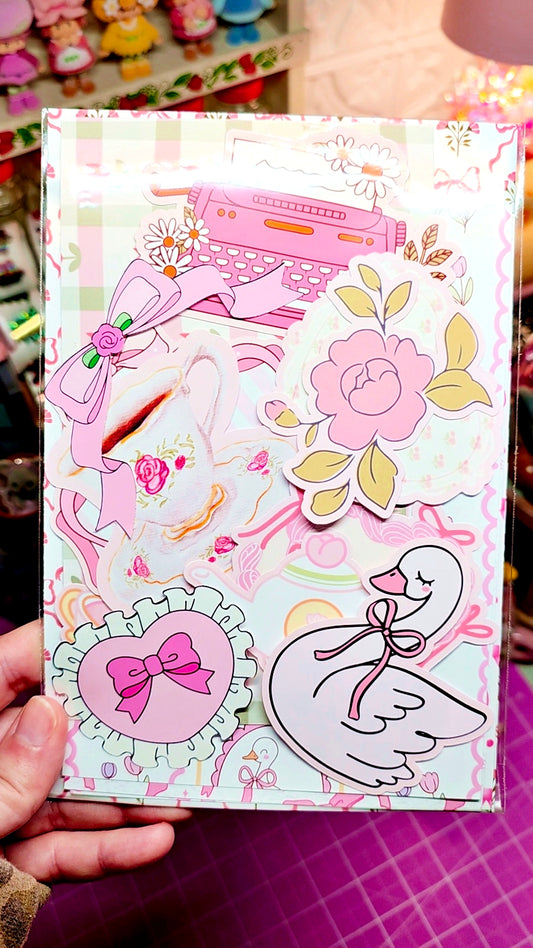 Decorative notebook with floral and bow designs held by a person.