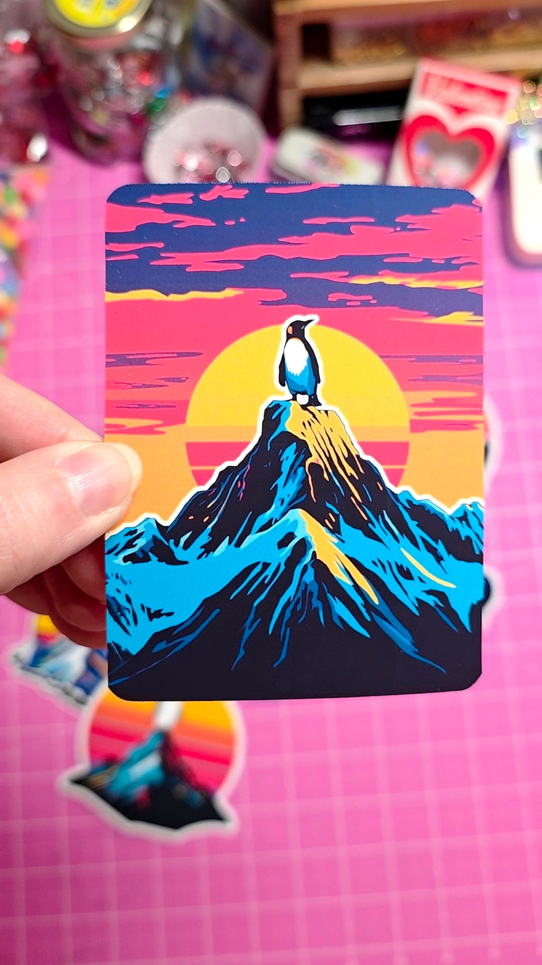 Colorful card with a mountain and bird design held against a pink background