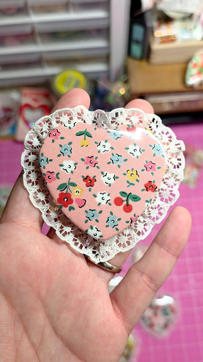 Heart-shaped decorative item with floral patterns held by a hand