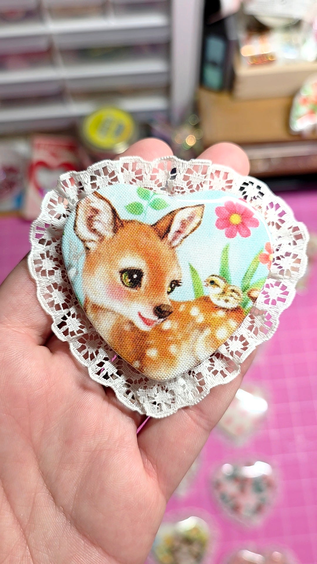 Decorative brooch with a deer design held in a hand against a blurred background