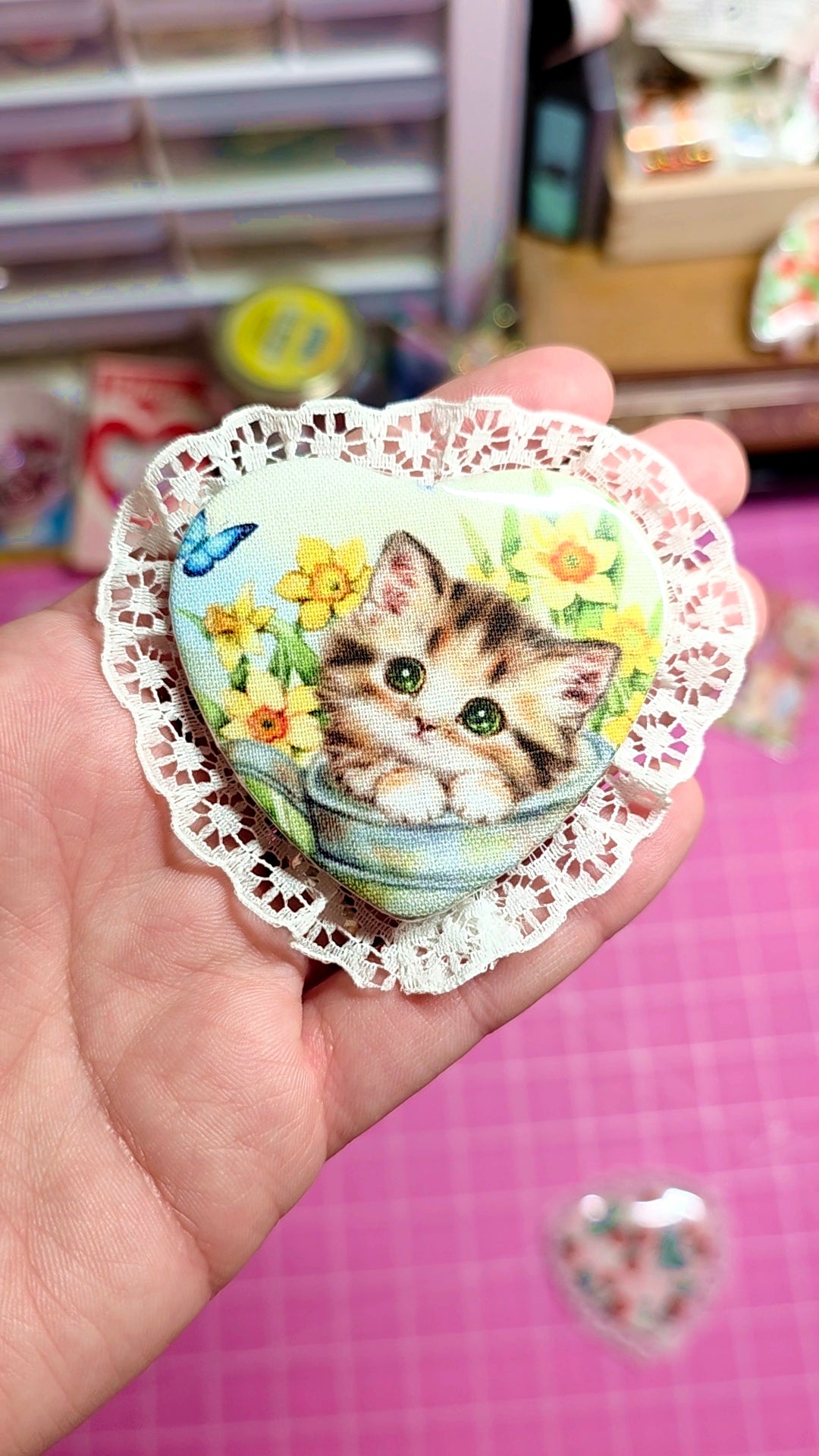 Decorative paper with a cat illustration on a doily held in a hand against a blurred background.
