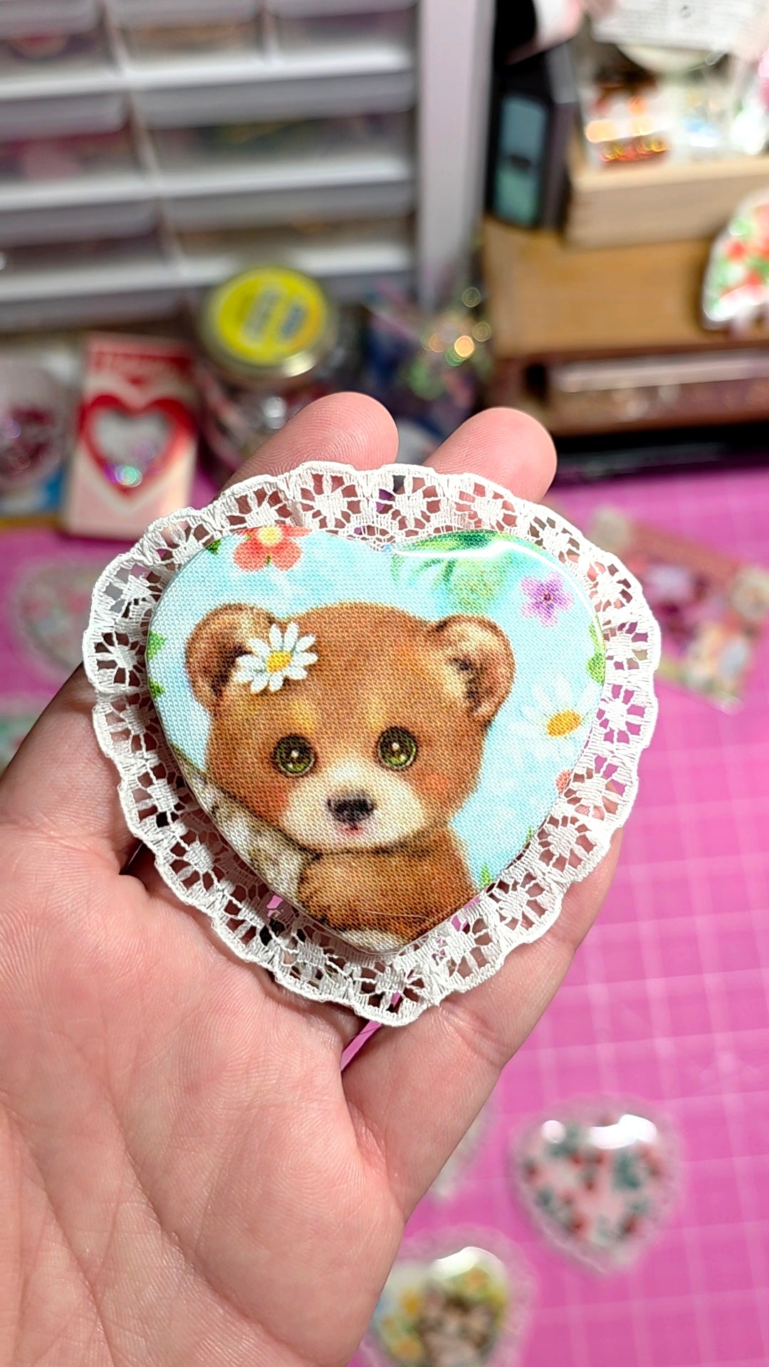 Sticker of a bear with flowers held in a hand against a blurred background