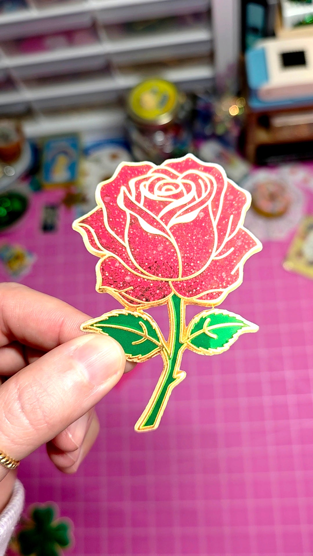 Hand holding a rose-shaped sticker with a blurred background