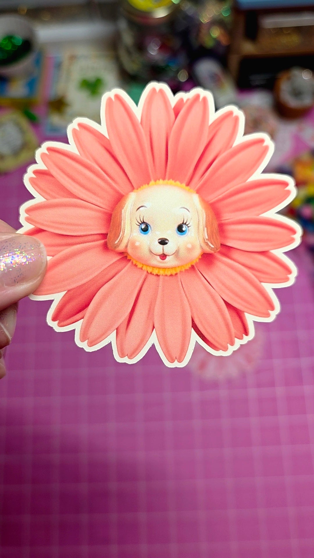 Floral-shaped sticker with a character face in the center on a pink background