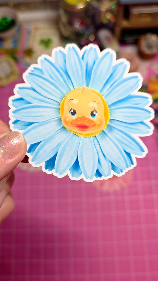 Sticker of a duck face on a blue flower with a blurred background