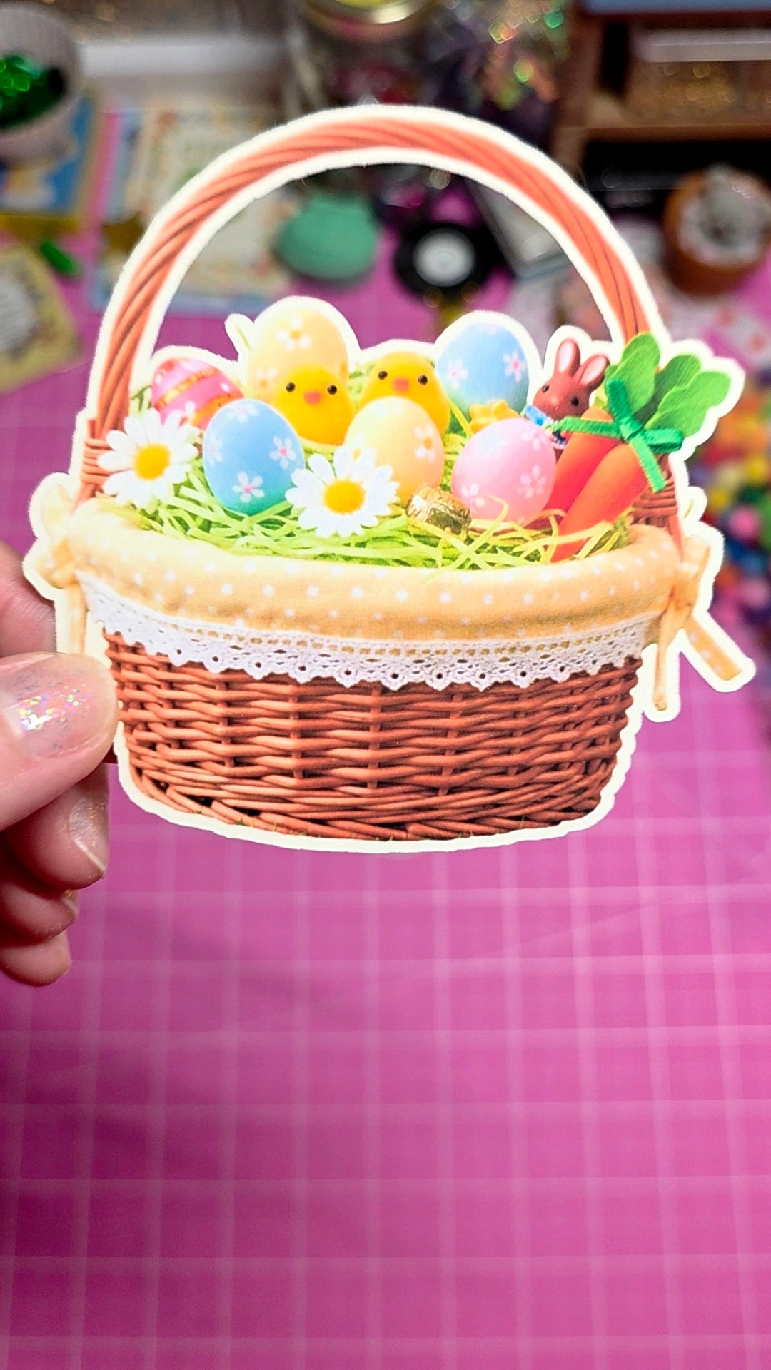 Decorative Easter basket with chicks, eggs, and carrots on a pink background