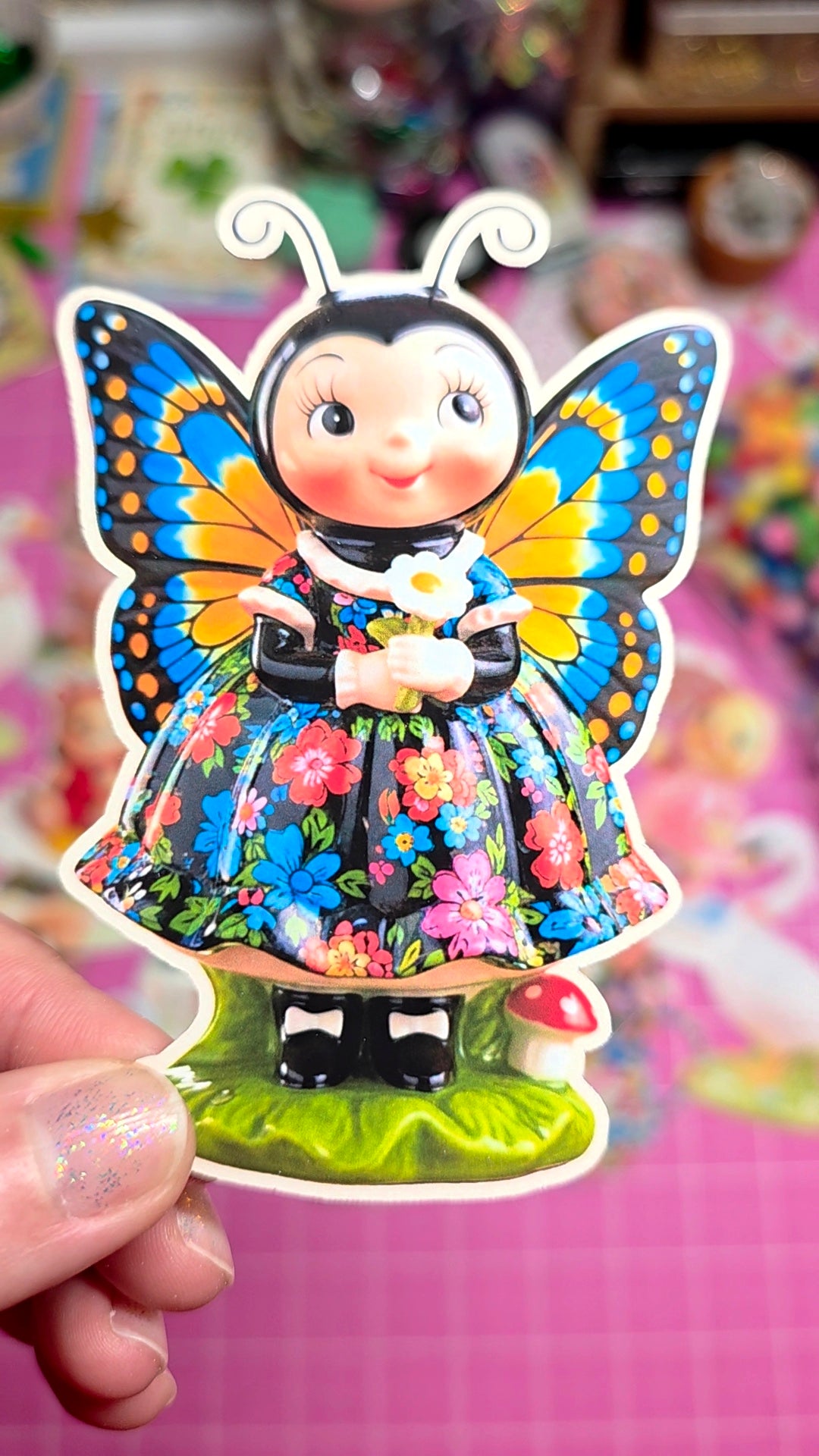 Colorful butterfly-themed figurine held by a hand against a blurred background