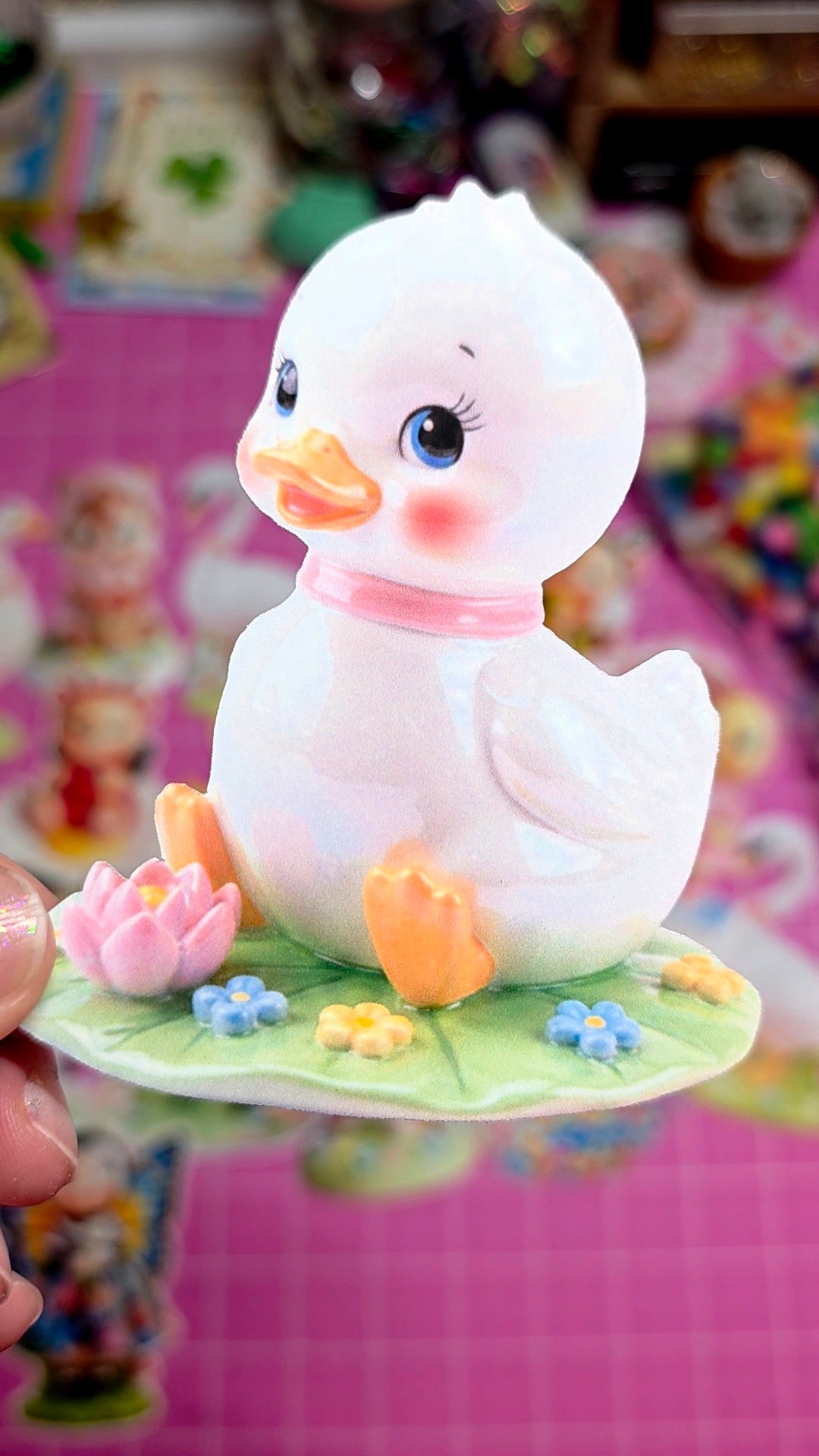 White duck figurine with pink bow on a pink background
