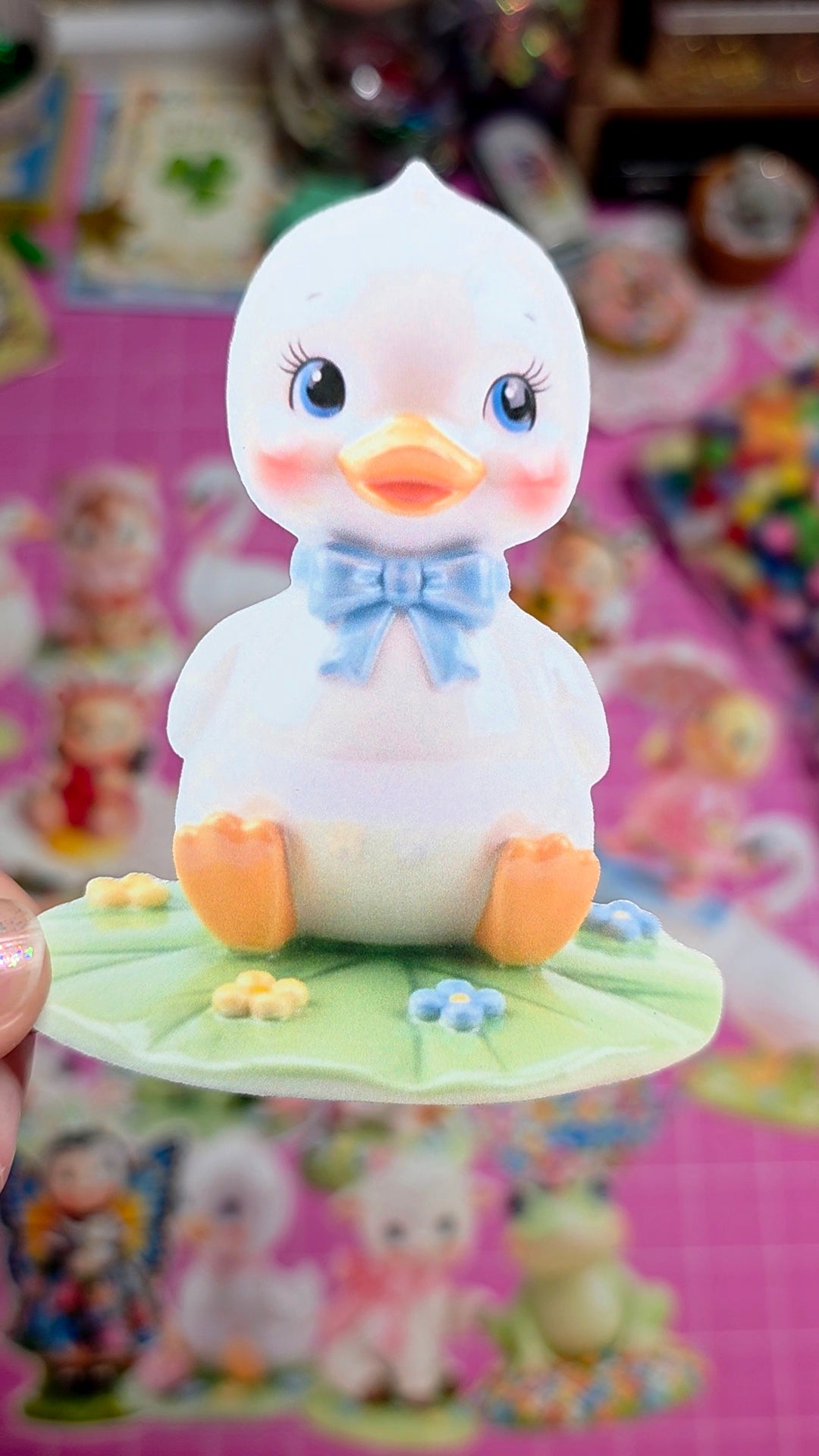 Small duck figurine with a bow tie on a pink background