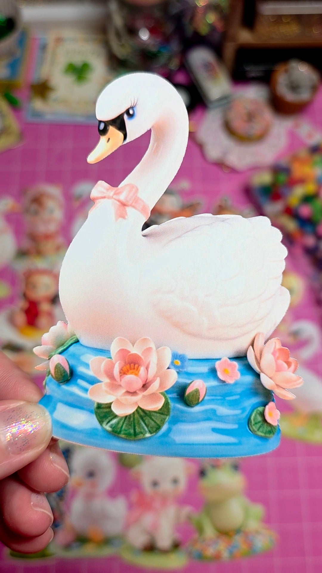 Decorative swan figurine with a pink bow on a colorful background