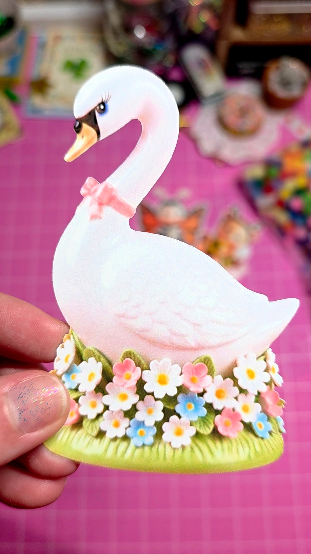 Decorative swan figurine with flowers on a pink background