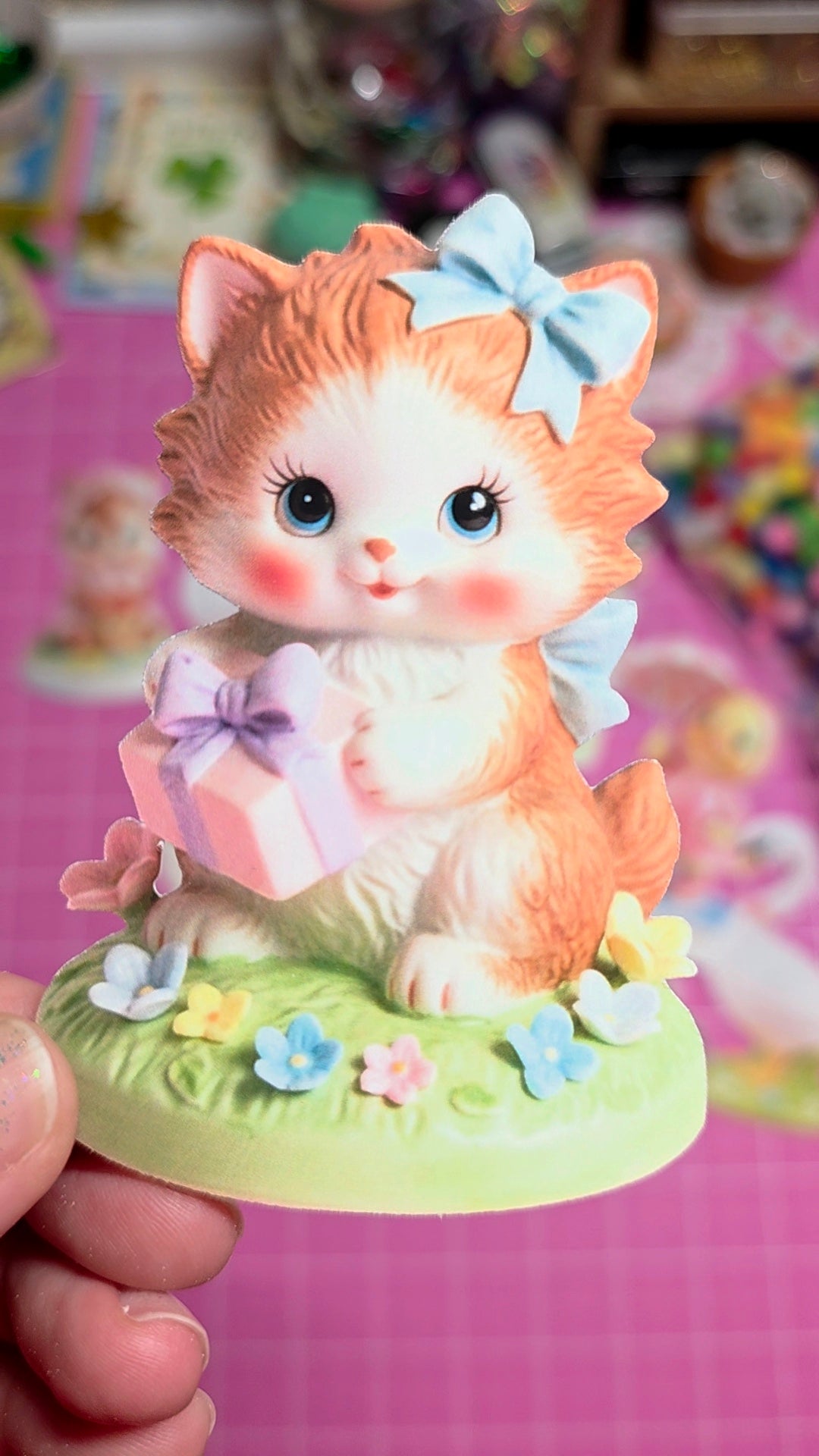 Decorative figurine of a cat with a bow on a pink background
