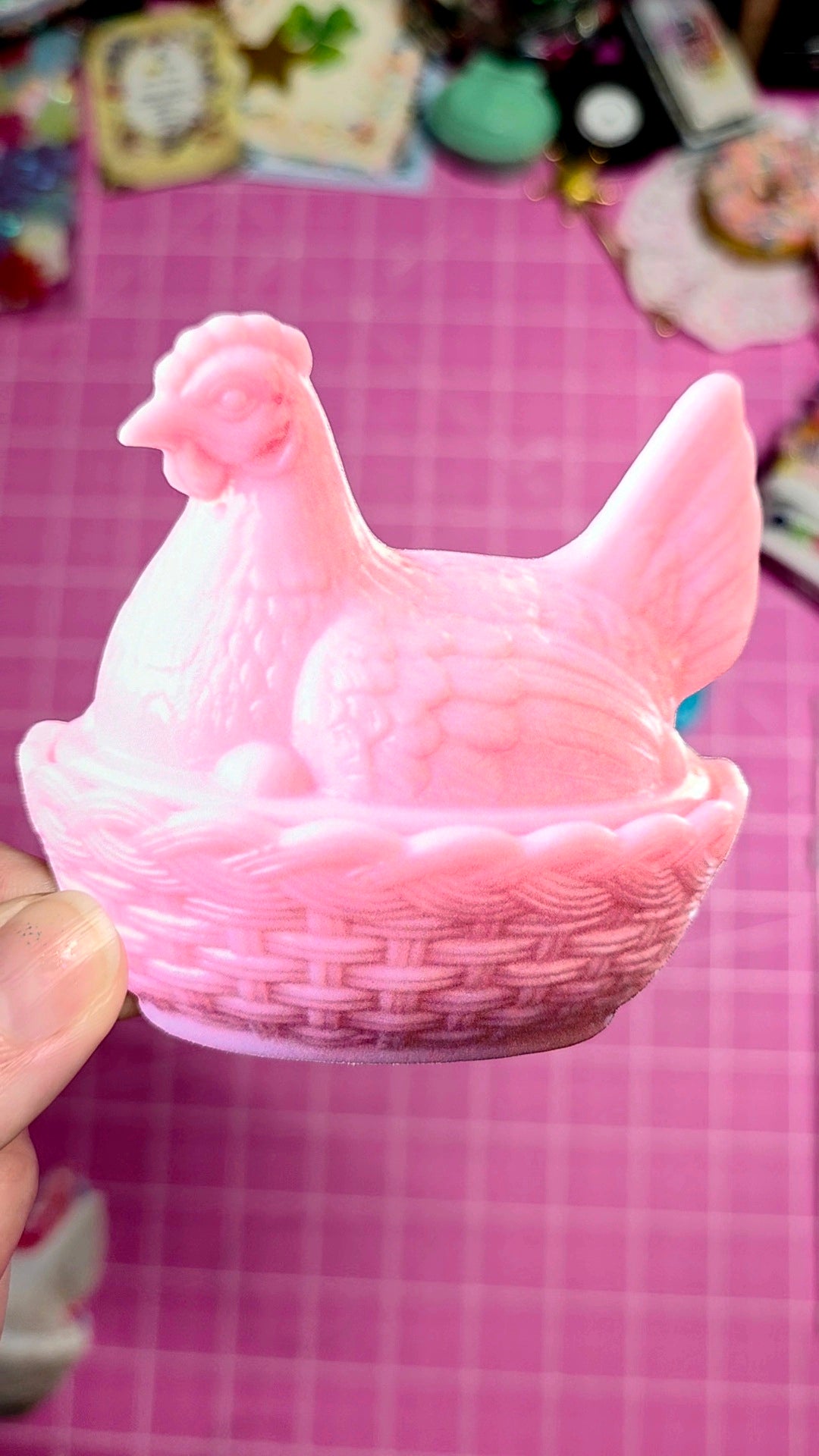 Pink ceramic chicken in a basket on a pink checkered background