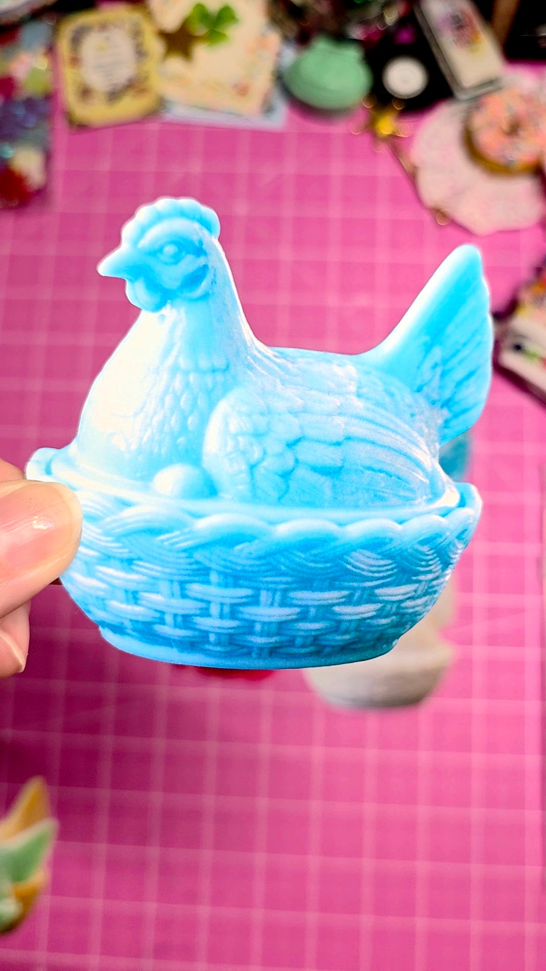 Blue ceramic chicken-shaped object on a pink surface