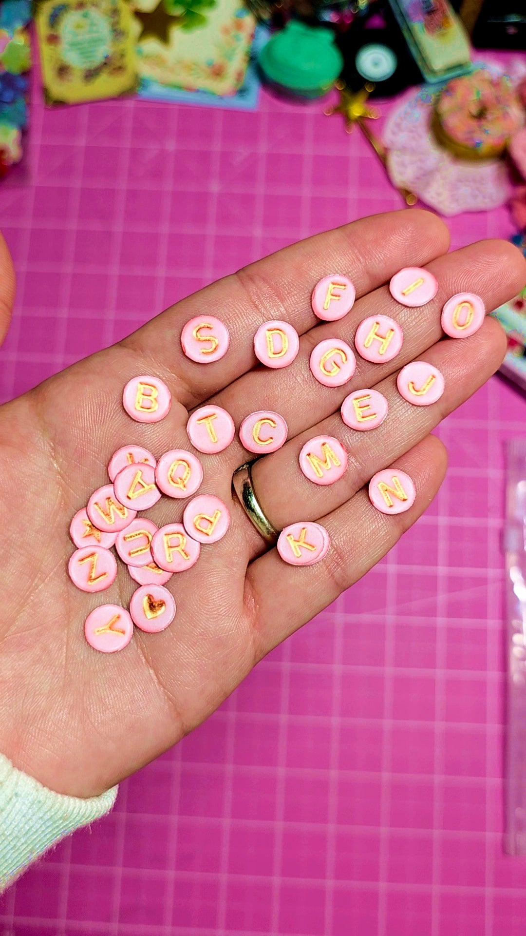 Hand holding pink letter candies on a pink grid background