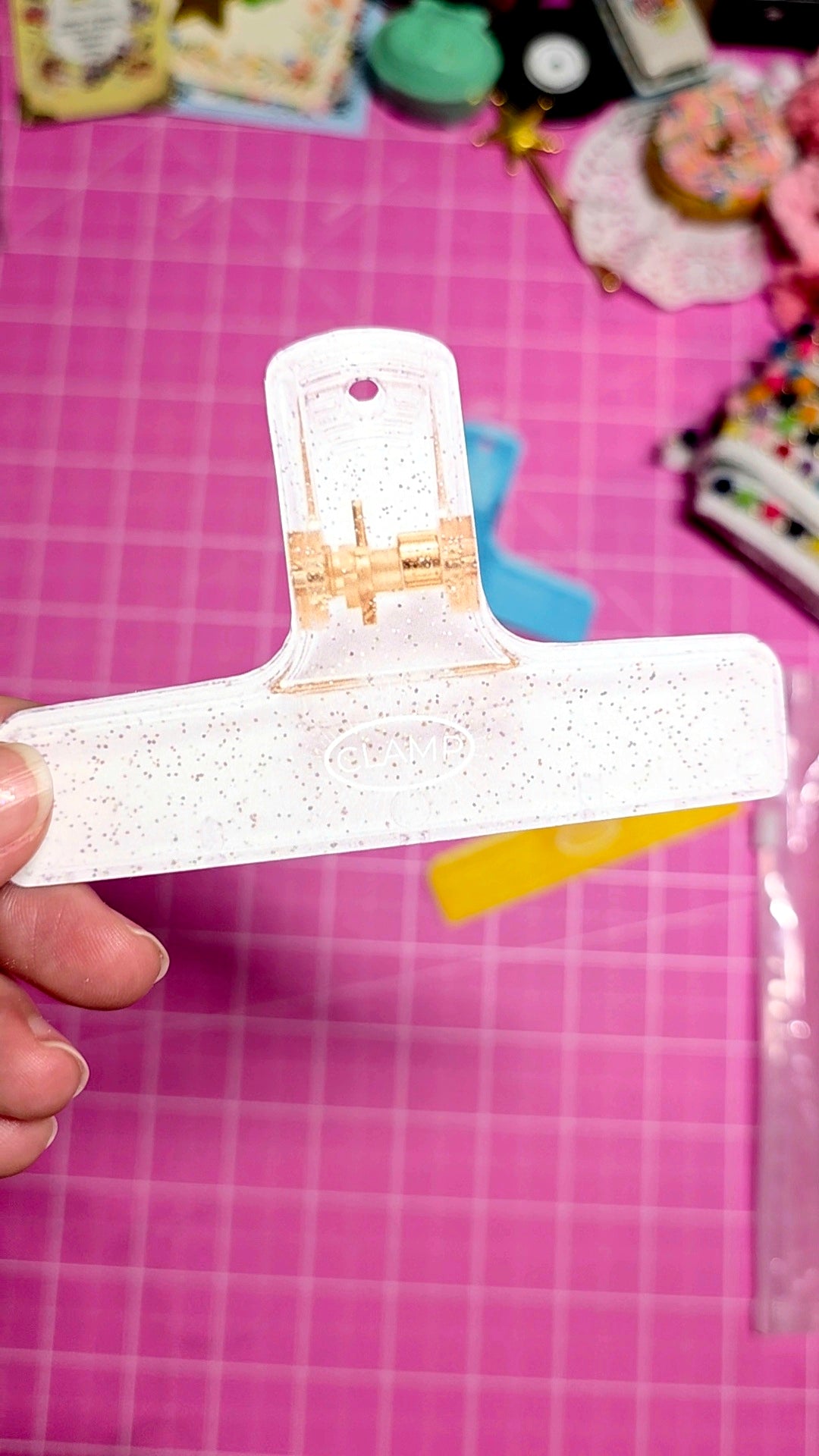 White paper clip with gold design held over a pink cutting mat.