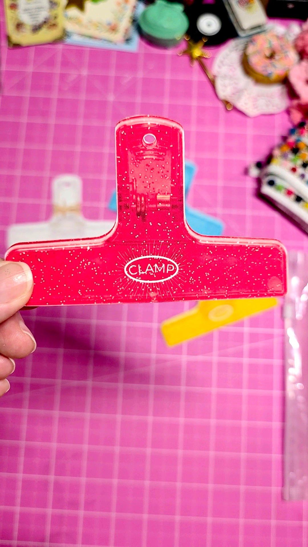Red clamp held over a pink cutting mat with various items in the background