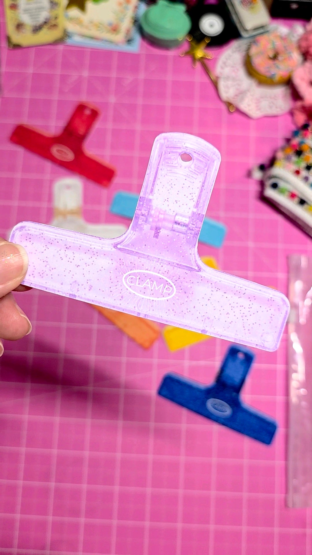 Clear plastic tool with blue handle on a pink grid background