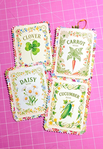 Four seed packets labeled 'Clover', 'Carrot', 'Daisy', and 'Cucumber' on a pink grid background.