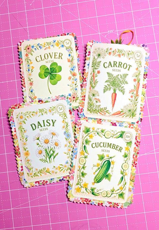 Four seed packets labeled 'Clover', 'Carrot', 'Daisy', and 'Cucumber' on a pink grid background.